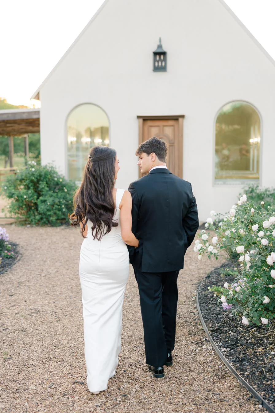 A couple walking the garden path toward the chapel at Gateley Hill Gardens