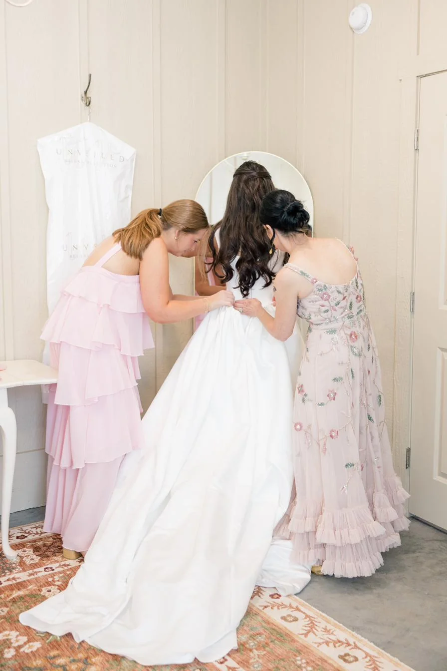 A bride being buttoned into her dress in the bridal suite at Gateley Hill Gardens